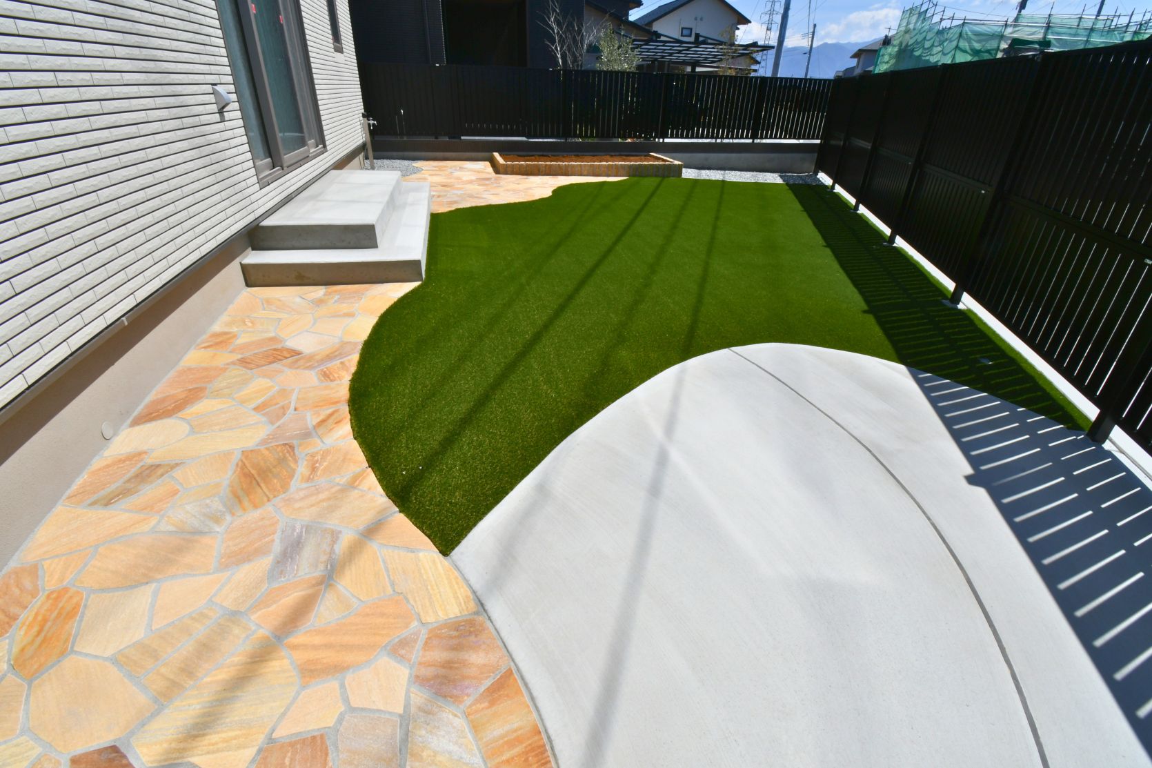 人工芝、乱形石、土間を美しく曲線で区切ったお庭